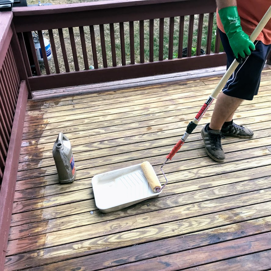 Applying Behr deck stain stripper to rejuvenate our old deck
