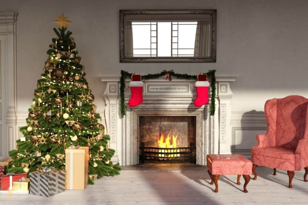 Lit Christmas tree placed next to lit cozy fireplace and comfy chair to show Home Safety During the Holidays