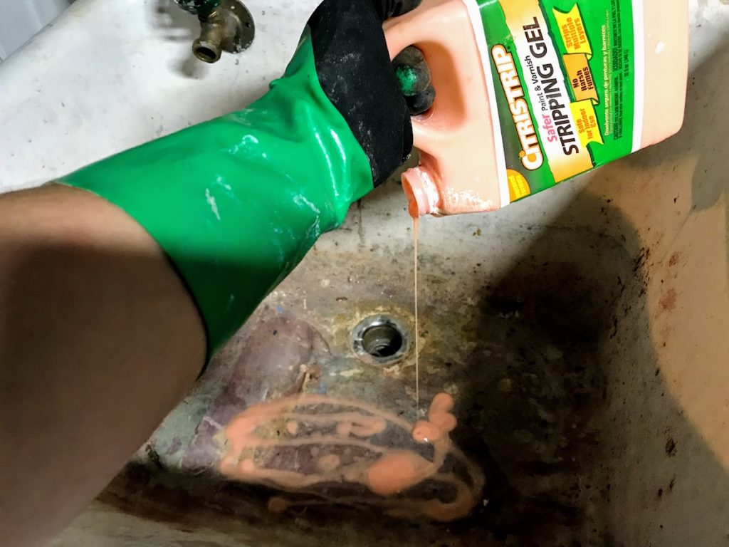 Pouring Citristrip into old slop sink to remove old paint