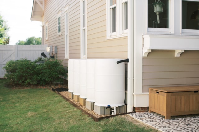 hide rain barrels by painting them to match the trim on your house