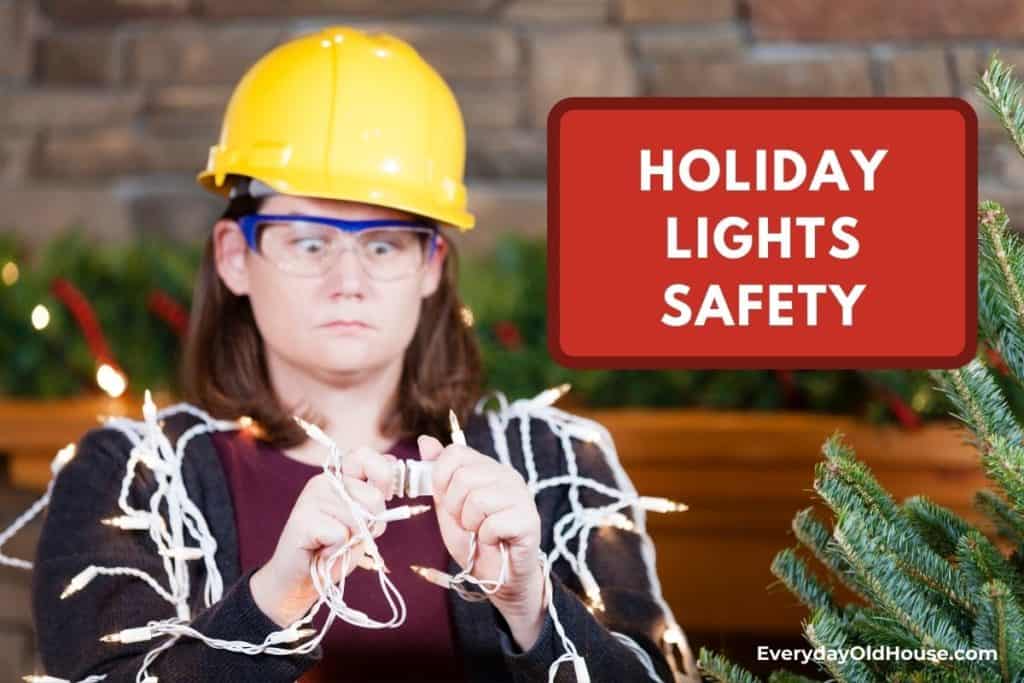 woman with safety hat cautiously hanging holiday lights