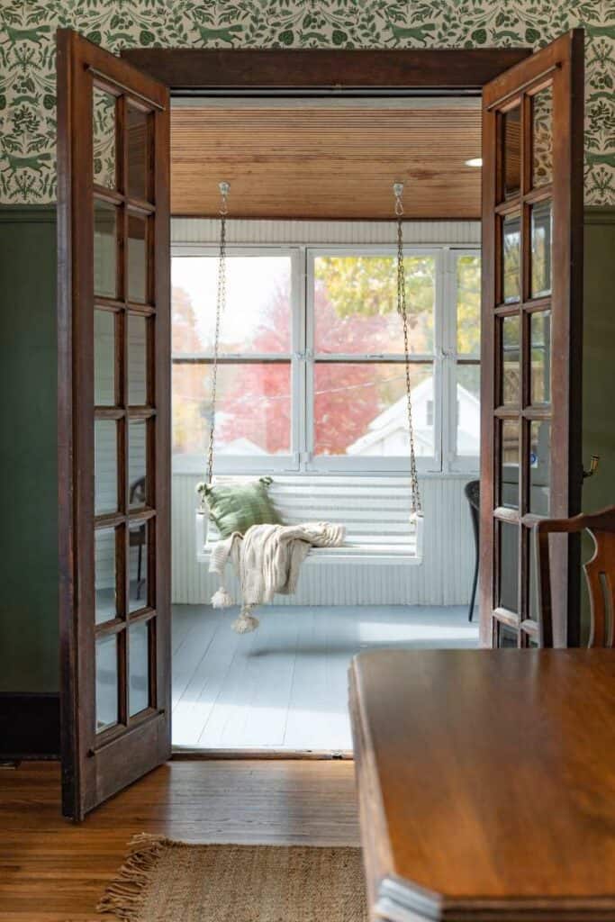Porch swing in distance seen through opened beautiful wooden french doors