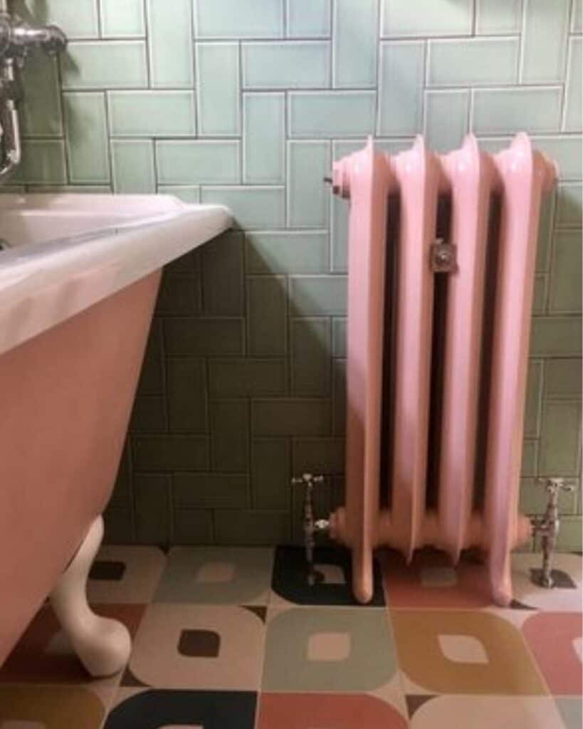 pink cast iron radiator that fits perfectly with an old cast iron tub with a modern tile floor