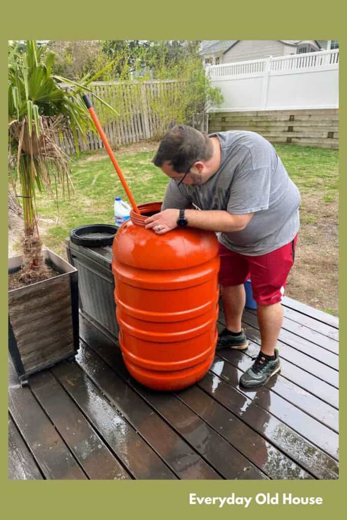 homeowner cleaning out rain barrel as part of fall maintenance