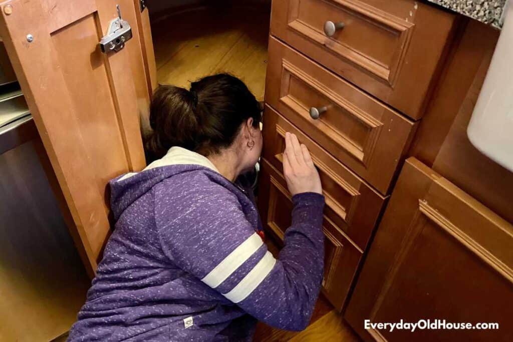 woman reaching deep into lazy susan to clean it - takes a bit of yoga poses!
