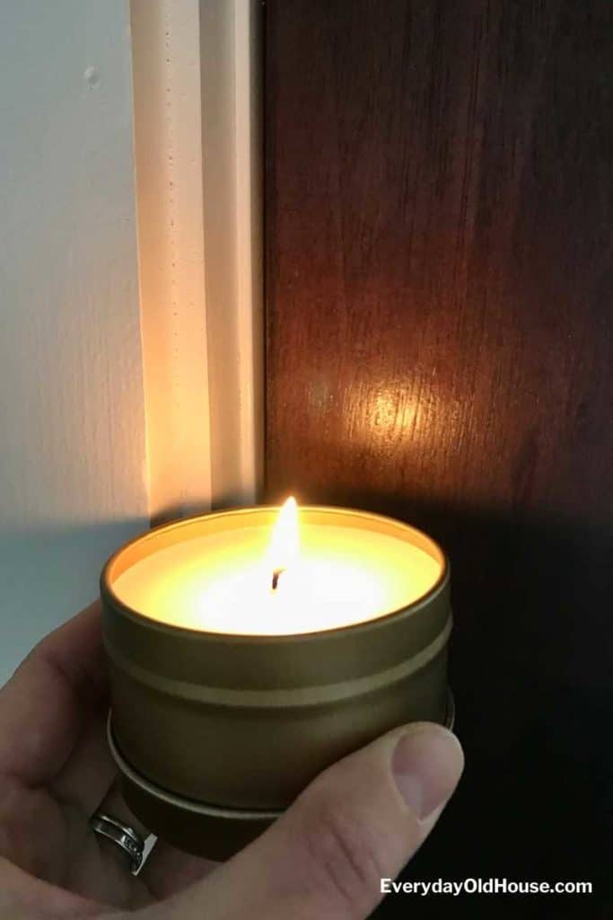 lit candle held to door frame to detect warm air escaping